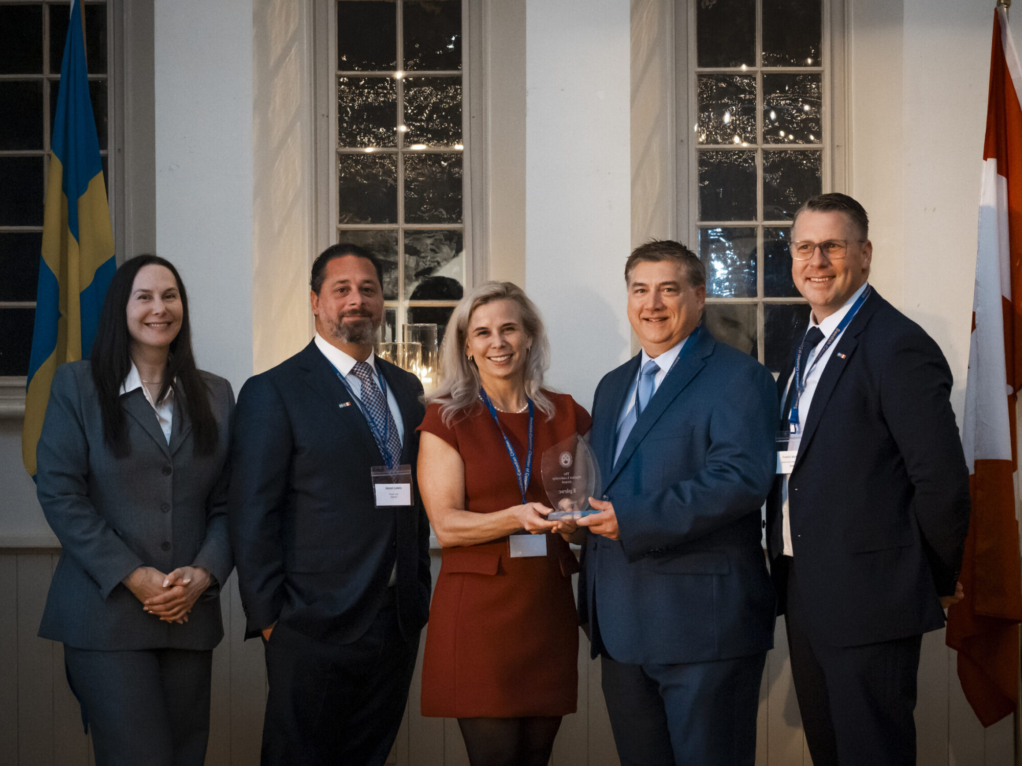 ferm-emelie_DSC2375_sccc-60th_jpg Two women and three men posing for a group photo while holding an award in front of Canadian and Swedish flags at a Swedish-Canadian Chamber of Commerce event.