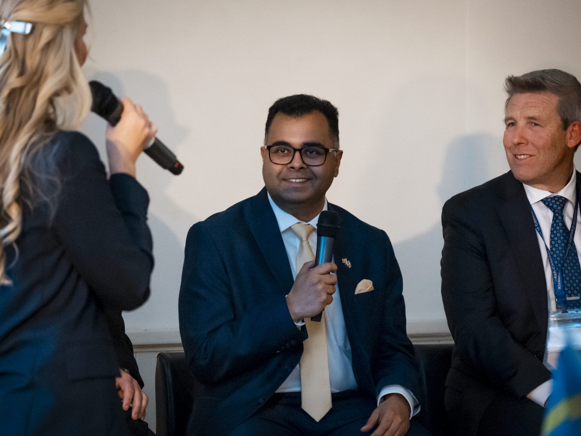 ferm-emelie_DSC2257_sccc-60th Close up of a panel discussion with two men seated and a woman standing as the host