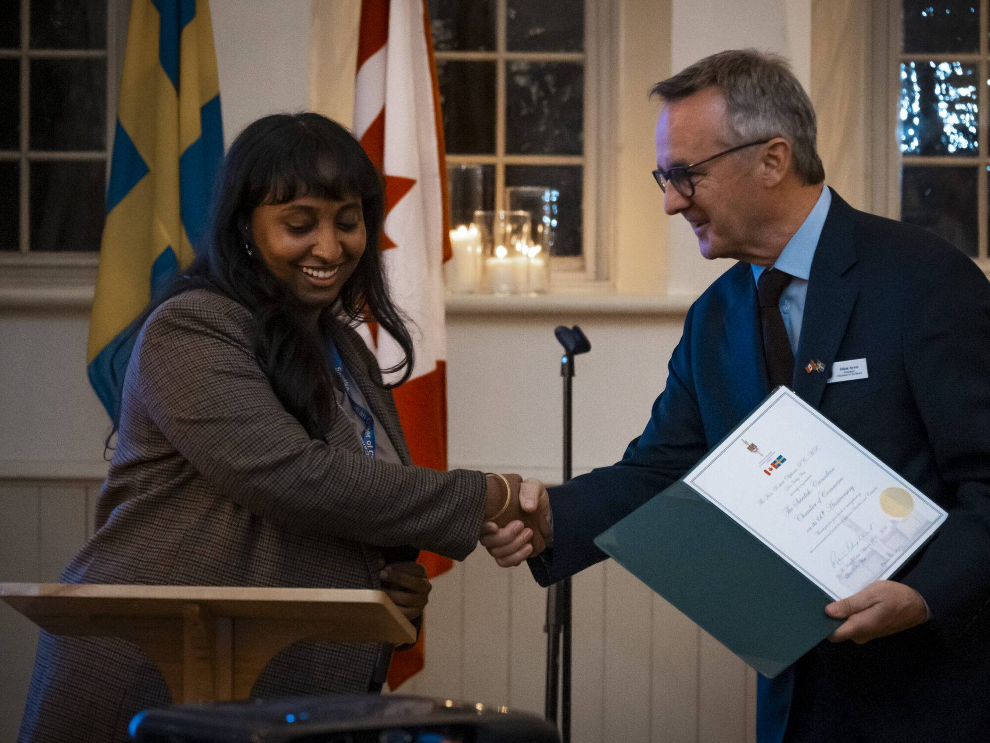 A man receiving a certificate from a woman and shaking her hand. A man receiving a certificate from a woman and shaking her hand.