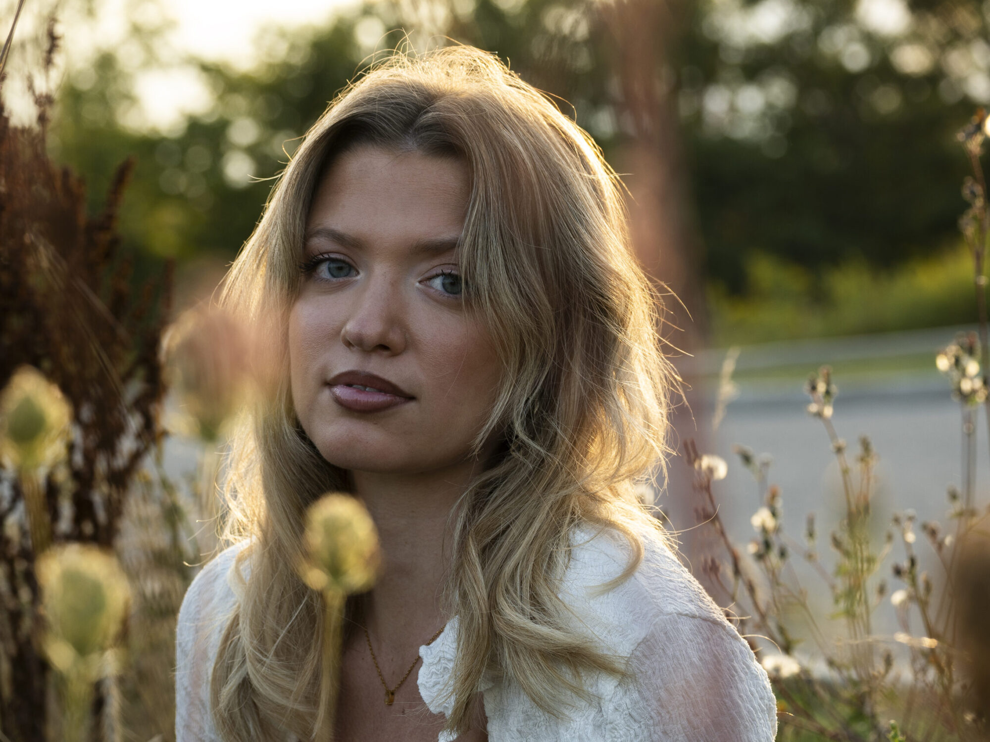 A portrait of a young woman outdoors, surrounded by soft-focus plants. A portrait of a young woman outdoors, surrounded by soft-focus plants.